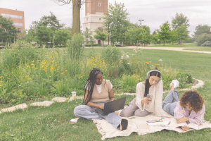Female college students sitting outside on campus talking together, highlighting social connection and college loneliness